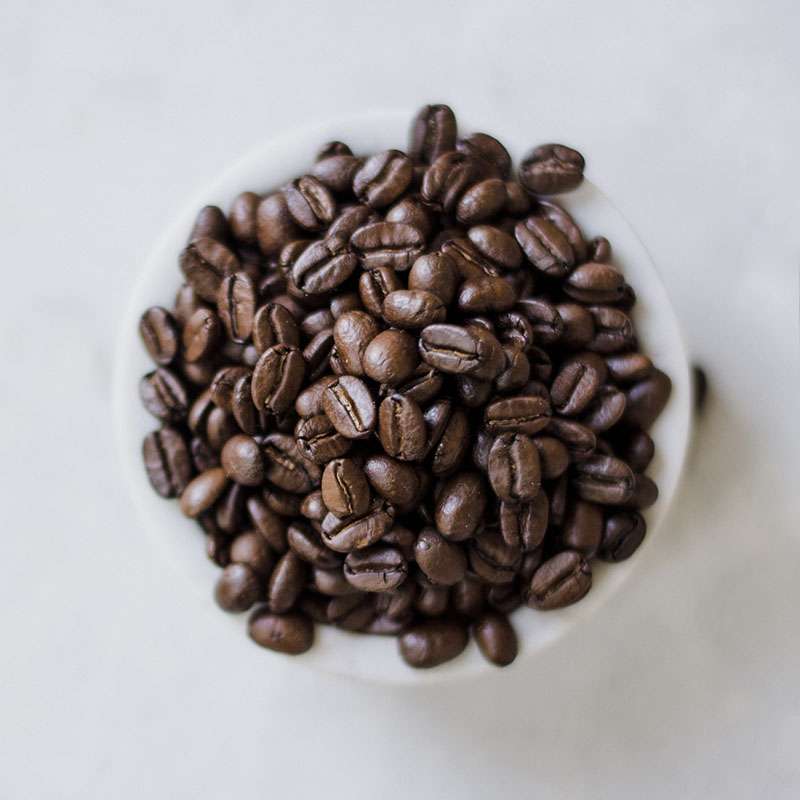 Top view of a cup full of roasted coffee beans
